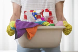 woman holding basket of cleaning supplies