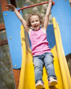 picture of a young girl going down the slide at a park