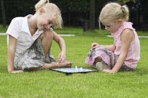 picture of 2 girls playing board games outside in the grass