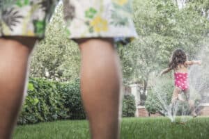 picture of a little girl running through sprinkler in the summer