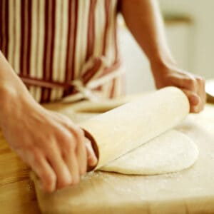 picture of a parent rolling out homemade pizza dough