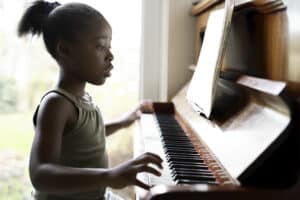 young girl playing piano as an indoor activity
