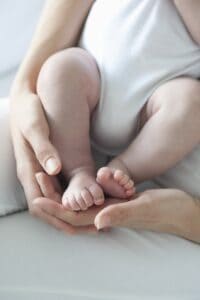 picture of a mother holding her newborn baby's feet while breastfeeding