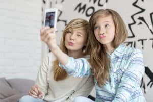 picture of two young girls smiling at a cellphone taking a selfie together