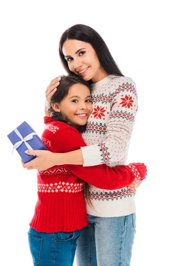 picture of a teacher holding a teacher Christmas gift while hugging a child