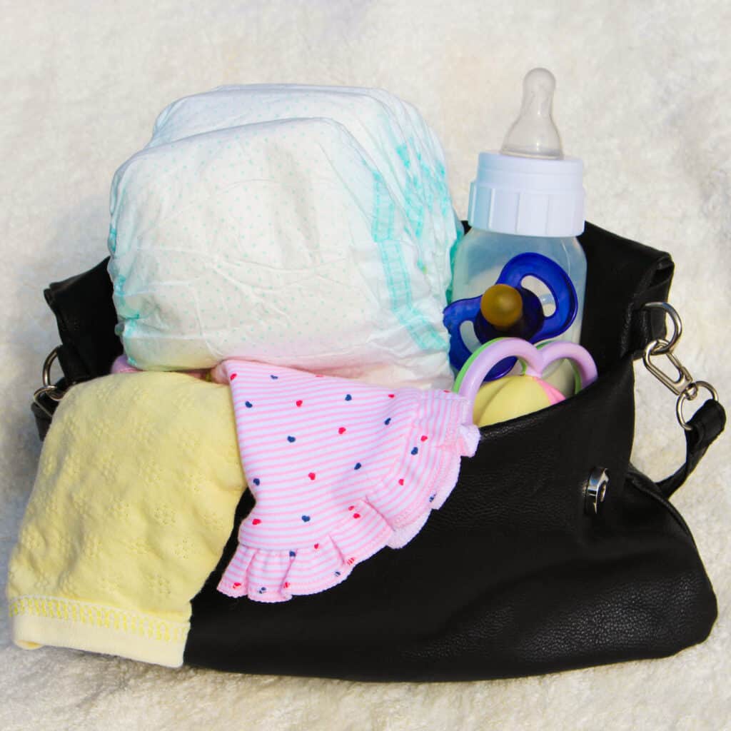 picture of a diaper bag for two kids with all the baby stuff spilling out of the top