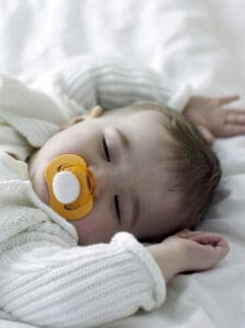 picture of a teething baby sleeping with a pacifier in their mouth