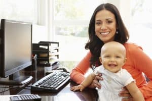 picture of a working mom holding her baby while sitting at her computer