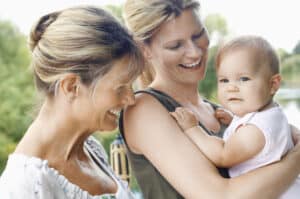 picture of a young mother holding her baby while the grandma looks on