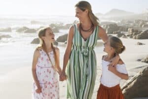 picture of a mother walking on the beach with her two school-aged daughters