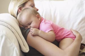picture of a mother laying on the couch sleeping with her baby
