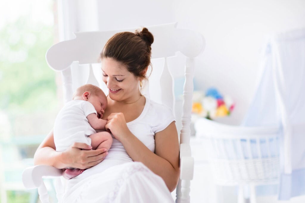 new mom holding her baby in their nursery