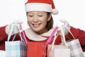 picture of a girl wearing a Santa costume while smiling and holding multiple Christmas shopping bags