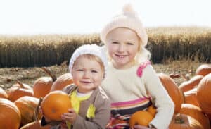 picture of two young kids at pumpkin patch in the fall