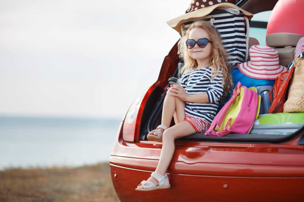 picture of a little girl ready for a family road trip sitting in the back of a car