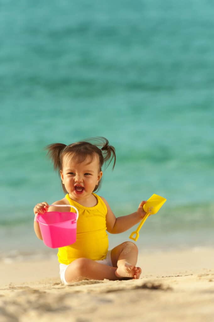 baby girl playing in the sand with sand toys at the beach