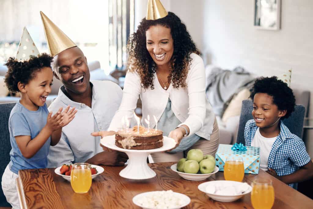 fun birthday celebration at home with a mom, dad, and kids smiling while having a birthday cake with candles