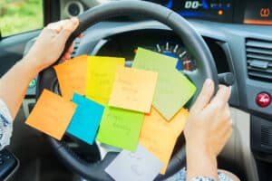 picture of a mom driving around with post-it notes on her steering wheel