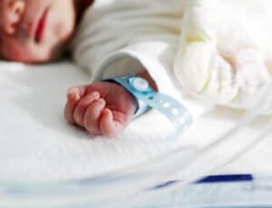 picture of a baby laying in the nicu with a hospital bracelet on their wrist