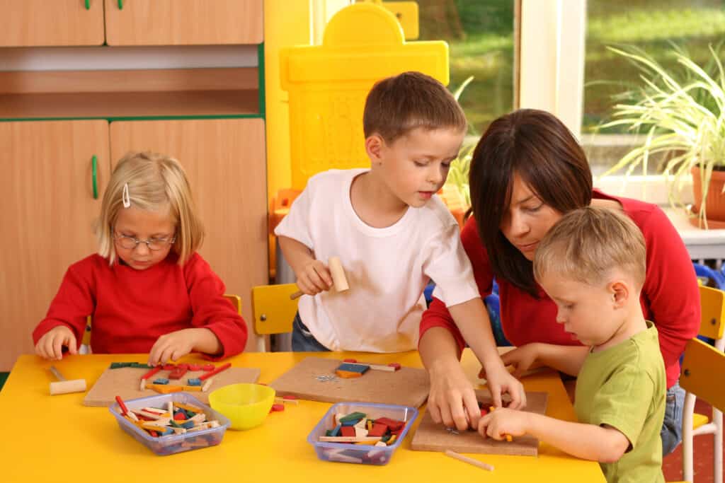 3 year old learning activity with other children and a teachers