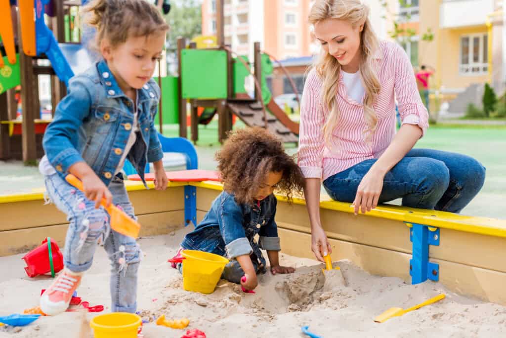 picture of a woman and her kids playing at the park as part of her stay at home mom routine