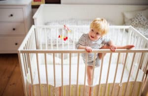 toddler trying to crawl out of the crib