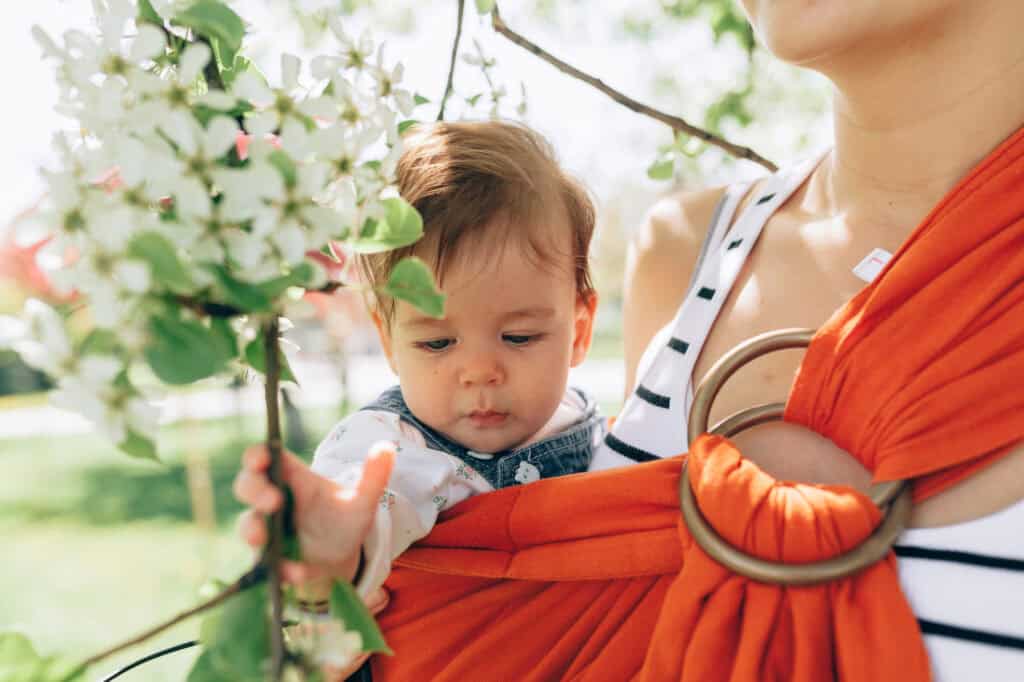 petite mom wearing a baby in baby sling