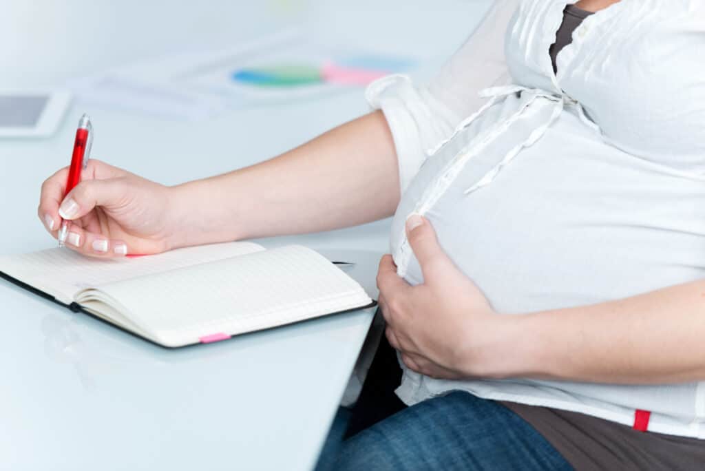 picture of a pregnant woman sitting at a desk working on creating a birth plan template