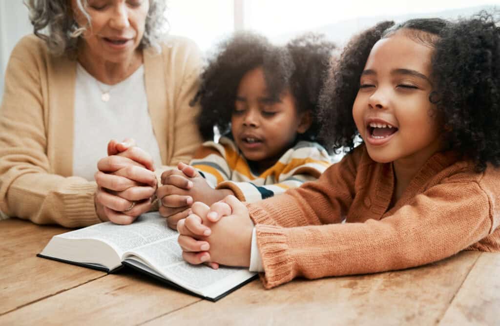 children praying with their mother