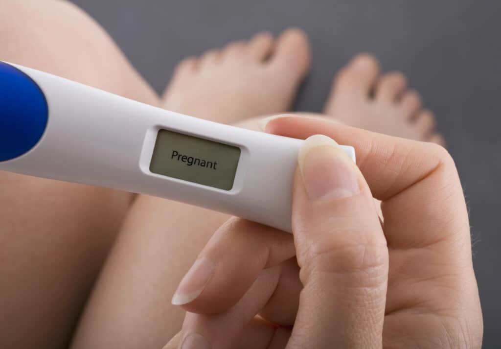 woman holding a positive pregnancy test after having very early pregnancy symptoms