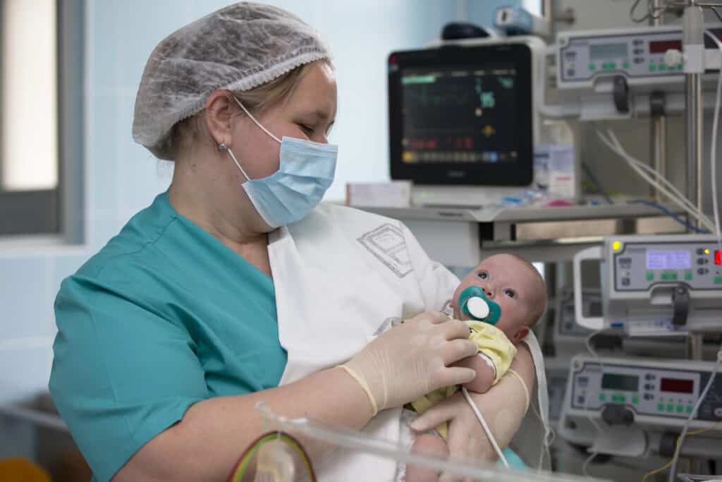 picture of a NICU nurse holding a baby in the NICU