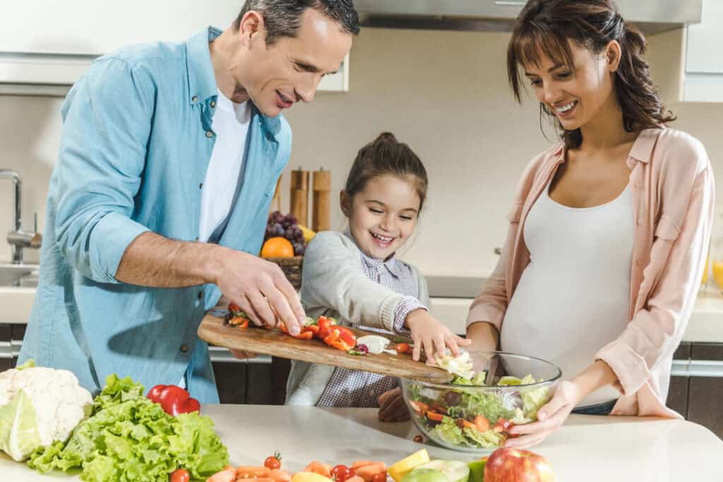 picture of a family working together to prepare a healthy meal with their pregnant mom