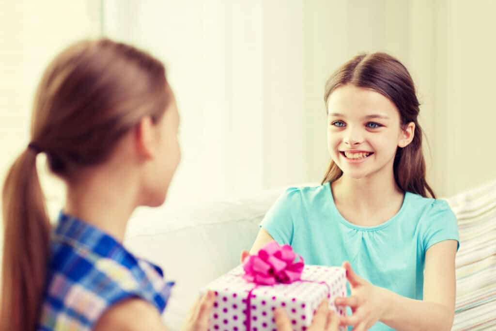 picture of a tween girl giving a gift for tween girls to another tween girl