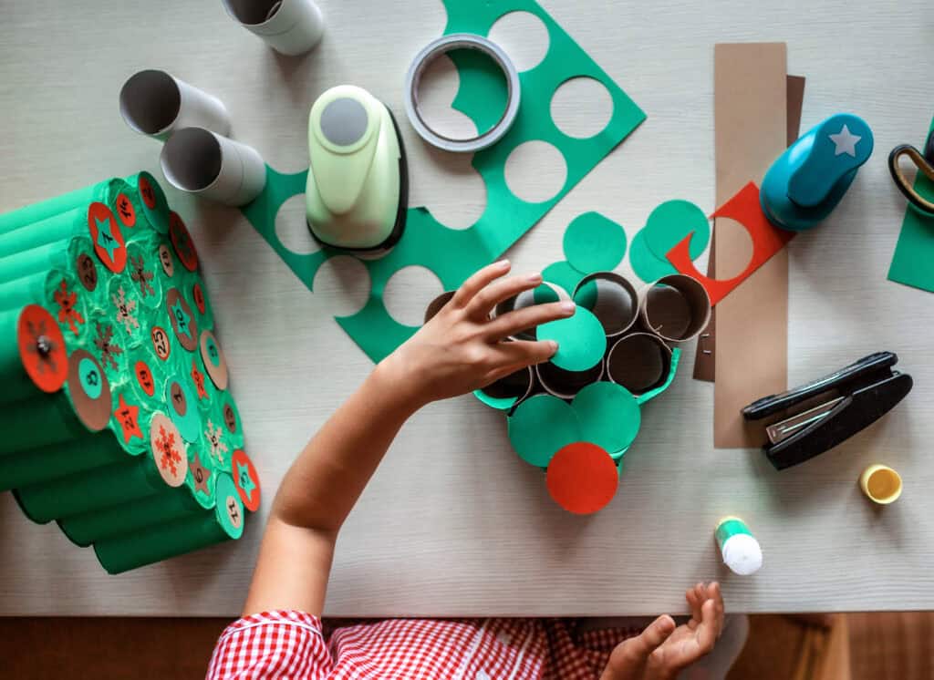 picture of a child creating an Advent calendar out of decorated toilet paper tubes