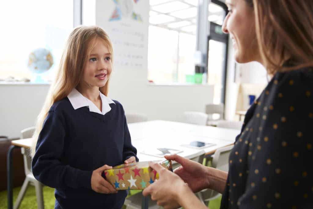 picture of a girl giving her teacher a first day of school teacher gift