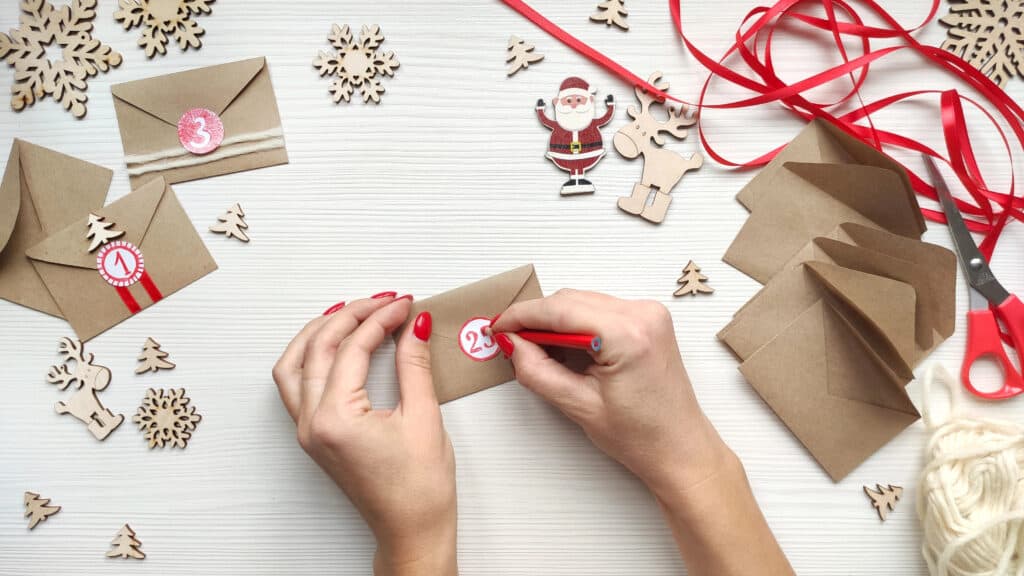 picture of a set of hands numbering Christmas themed envelopes to create an Advent calendar