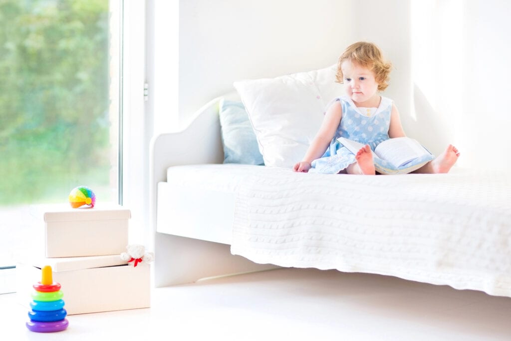 toddler girl sitting in her toddler bed