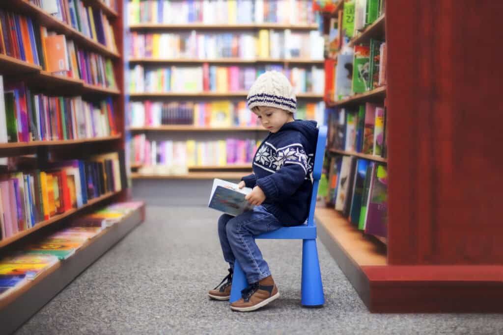 picture of a boy sitting in the library reading a Christian book for kids