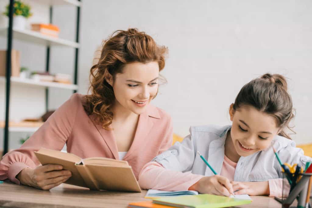 picture of a mother sitting at a table working on homeschool work with her daughter