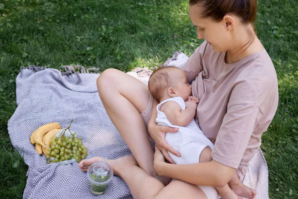 picture of a woman breastfeeding while eating a healthy snack for breastfeeding moms