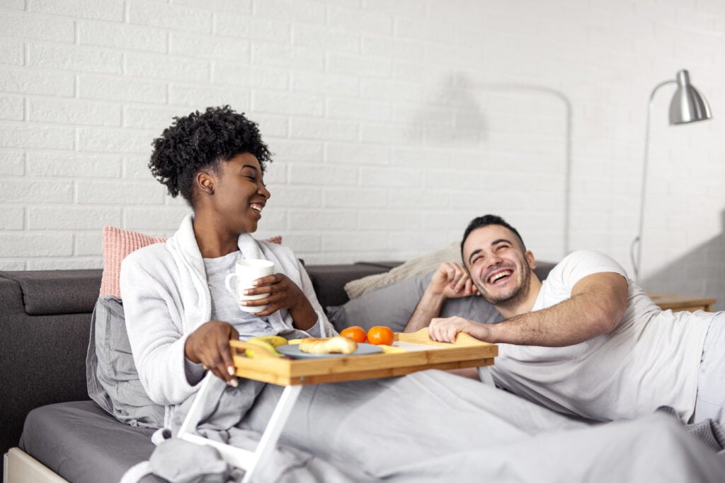 picture of a man holding a glass to his pregnant wife's belly pretending to hear the baby inside