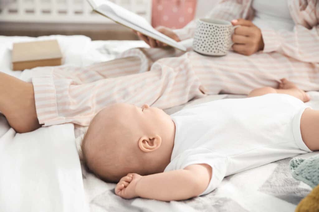 picture of a new mom journaling while her baby sleeps beside her