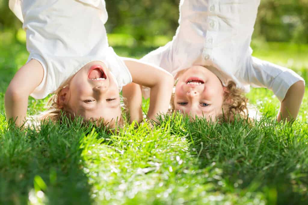 kids doing handstands in the grass playing outside in the spring