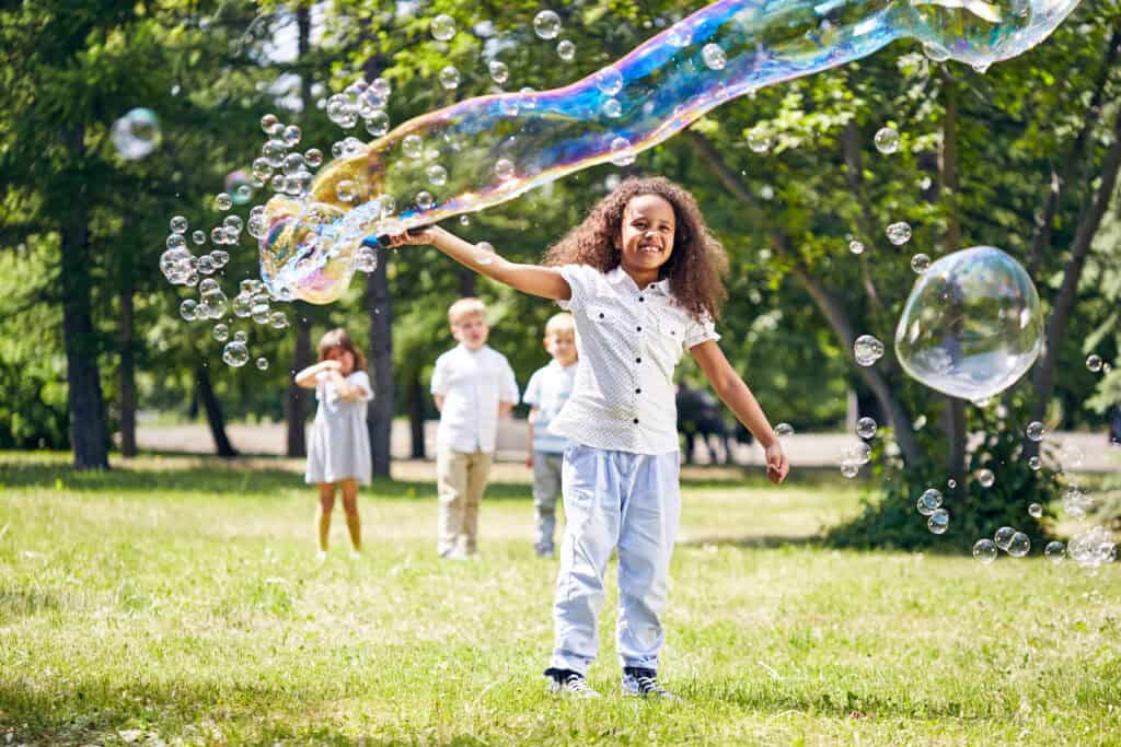 kids playing outside making large bubbles during the spring