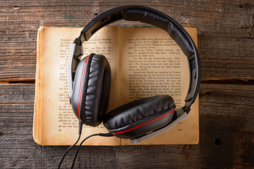 picture of a pair of headphones lying on an opened book on a wood floor